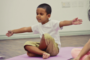 a kid is doing yoga at yoga mat in his house