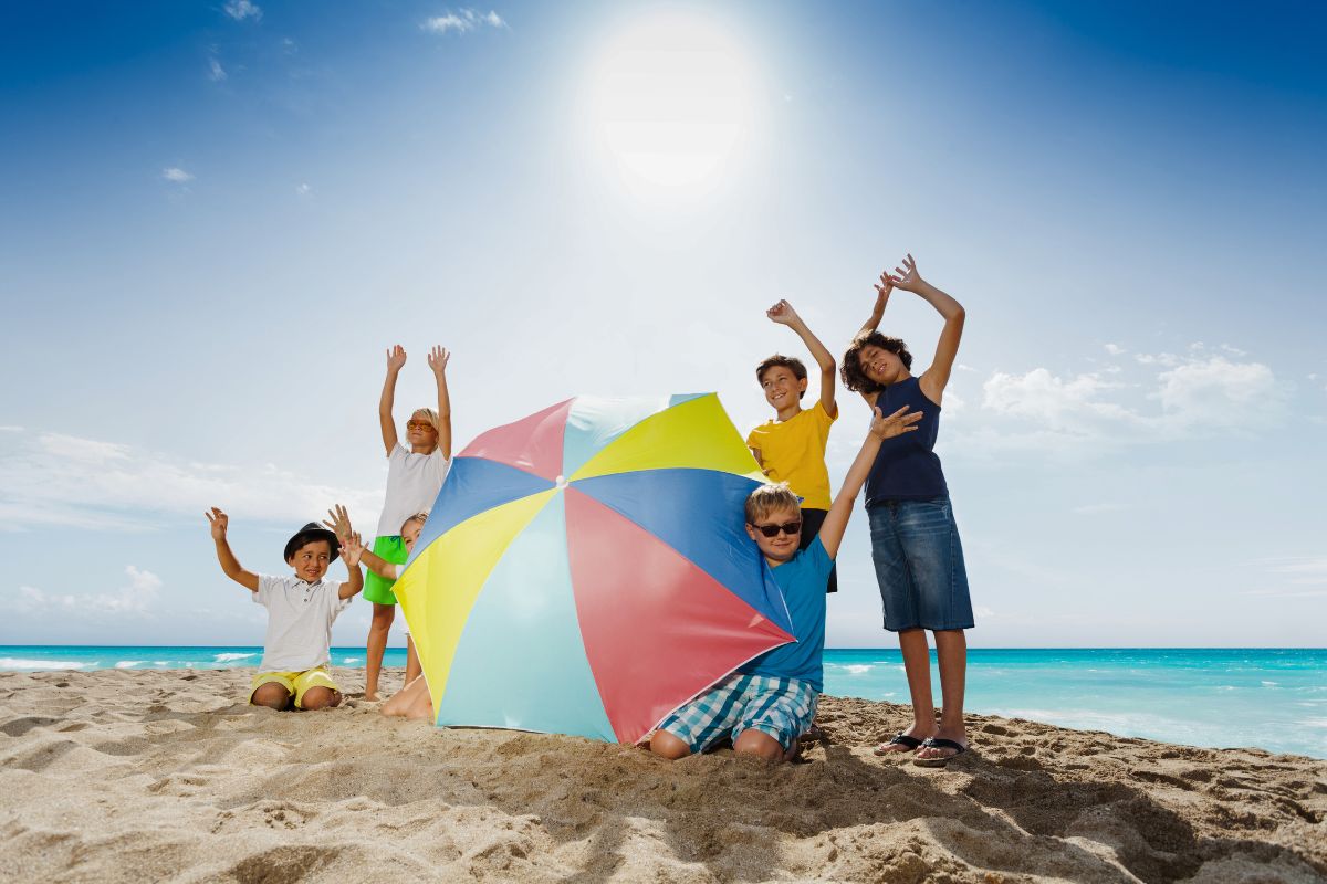 Kids playing on the beach under the sun with an umbrella