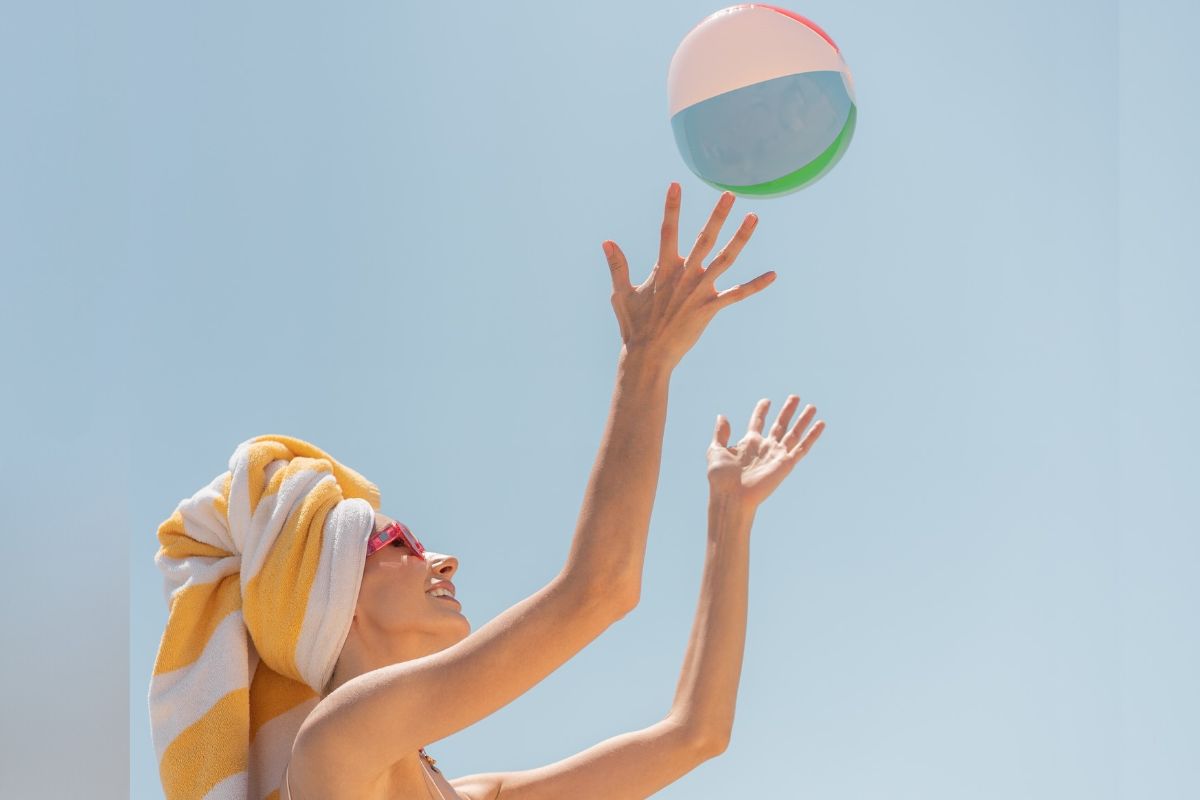 A lady with her head wrapped in towel playing with a beach ball at Al Bateen Ladies Beach in Abu Dhabi