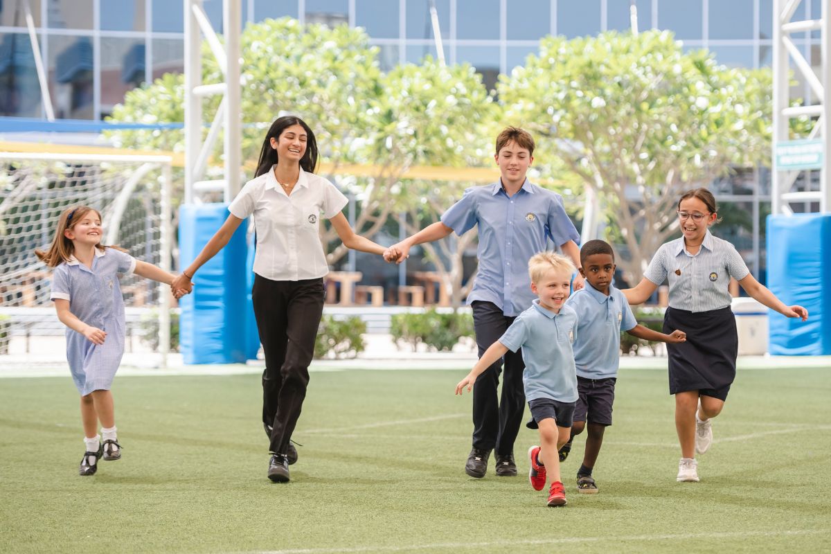 students from bsak abu dhabi school running through the school field