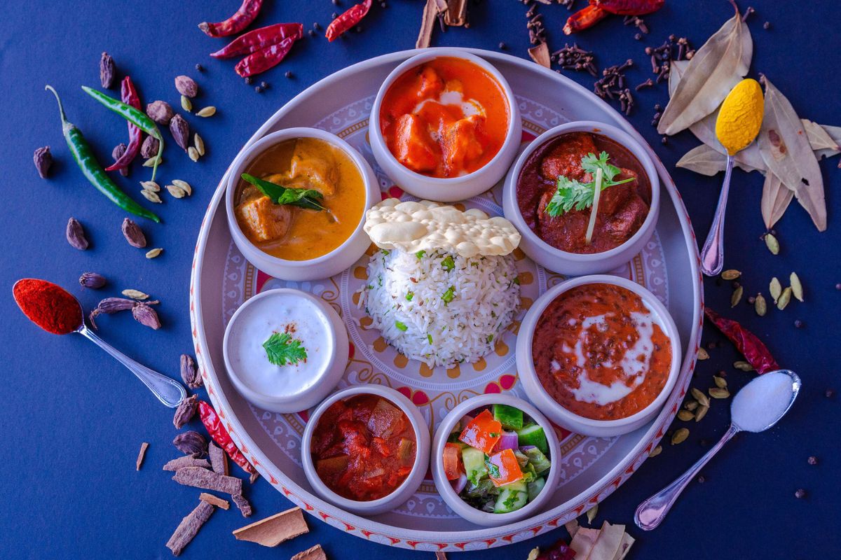 Beach Rotana Abu Dhabi business lunch features Indian spices like chili, cardamom, turmeric, garam masala with a sample plate of rice, butter chicken, red curry, pickled vegetables, raita and pappadam