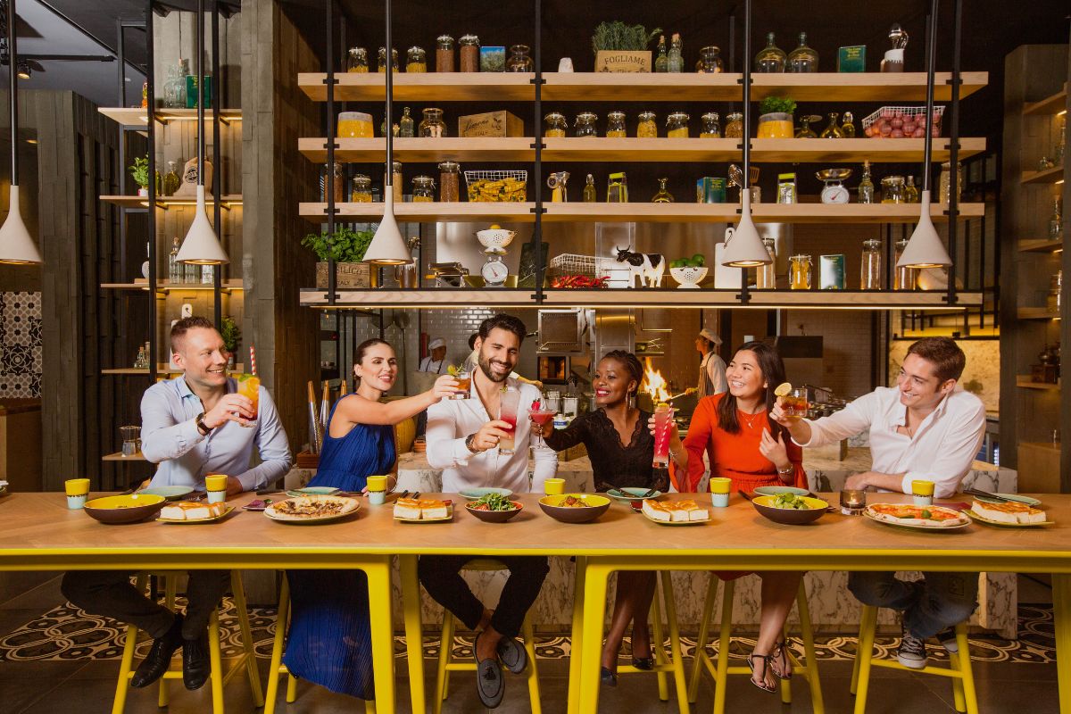 A group of people tossing their glasses while enjoying their meals at Verso Grand Hyatt Abu Dhabi summer offers