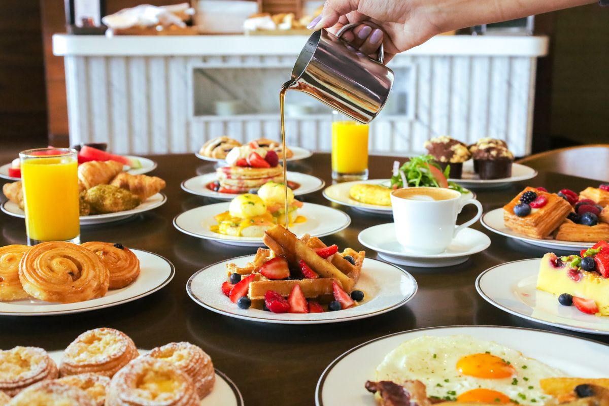 A table full of breakfast items like pastries, waffles, eggs fruits, juices, coffee and tea for Breakfast at Sahha Grand Hyatt Abu Dhabi Summer offers