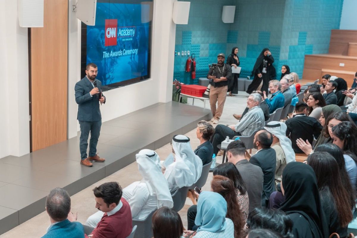 Inside the cnn academy abu dhabi awards ceremony with diverse people sitting down and listening to the speaker, cameraman on the side pointing the camera to the speaker