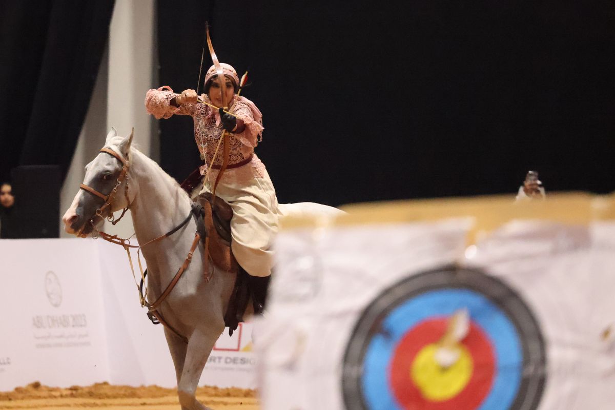 Lady riding a horse while doing archery at ADIHEX