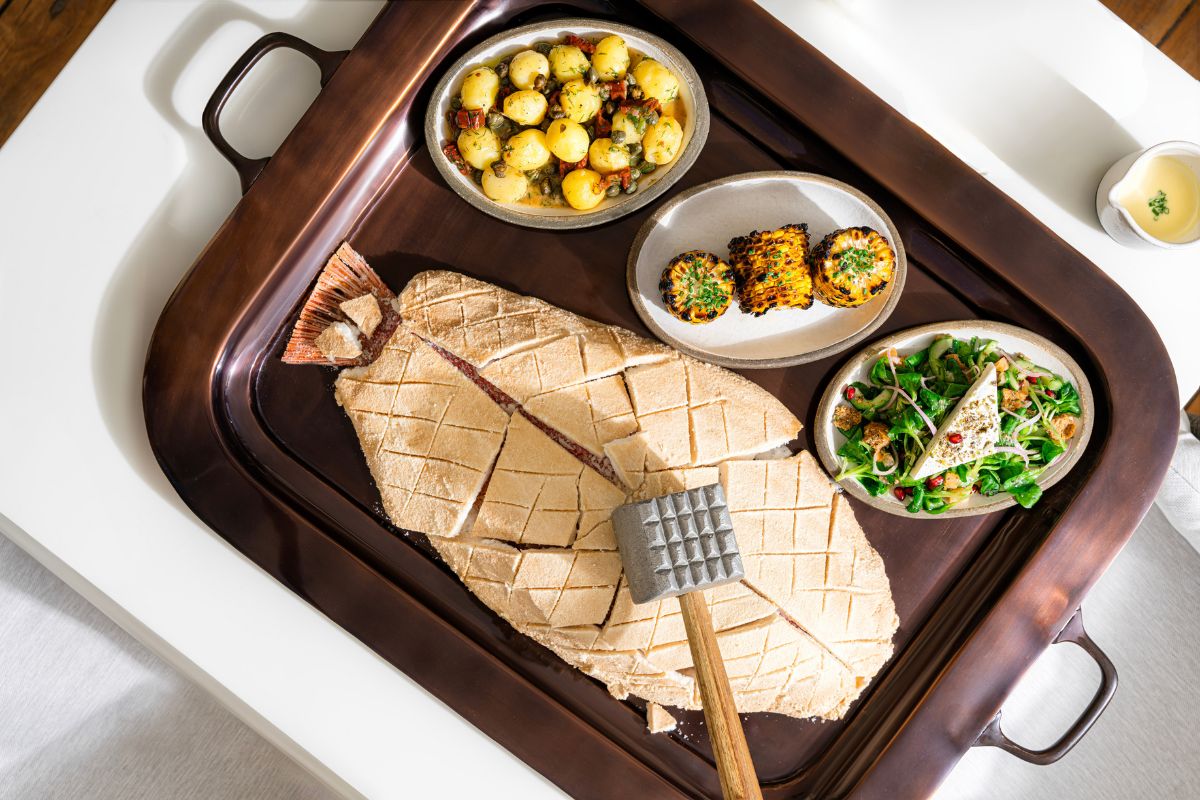 salt-crusted fish with a mallet to crush the cover, side dishes like herbed potatoes, chargrilled corn on the cob and green salad from MAZI at The St. Regis Saadiyat Island Resort