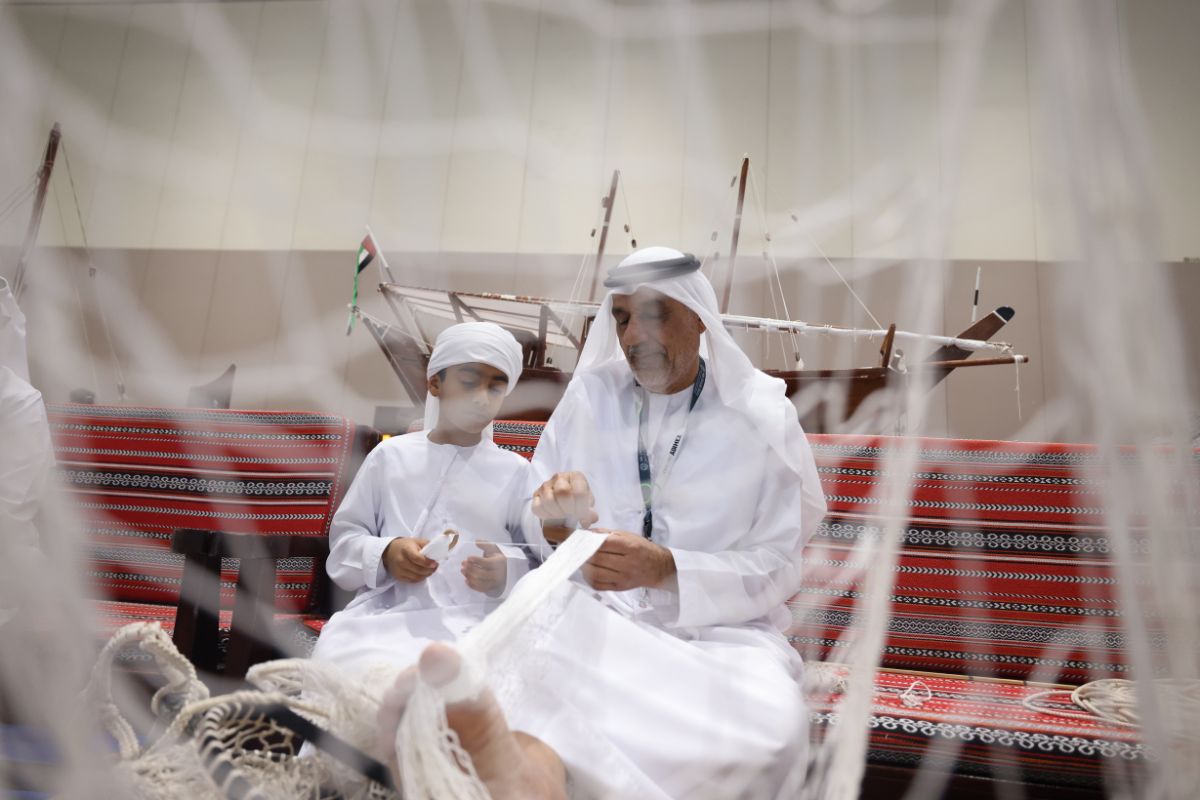 Man sewing a cloth while kid is assisting at ADIHEX