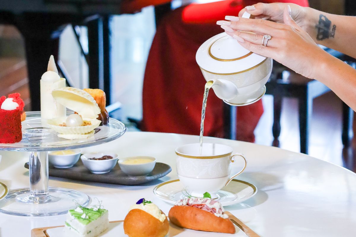 A lady pouring a cup of tea for Afternoon tea at Pearl Lounge Grand Hyatt Abu Dhabi