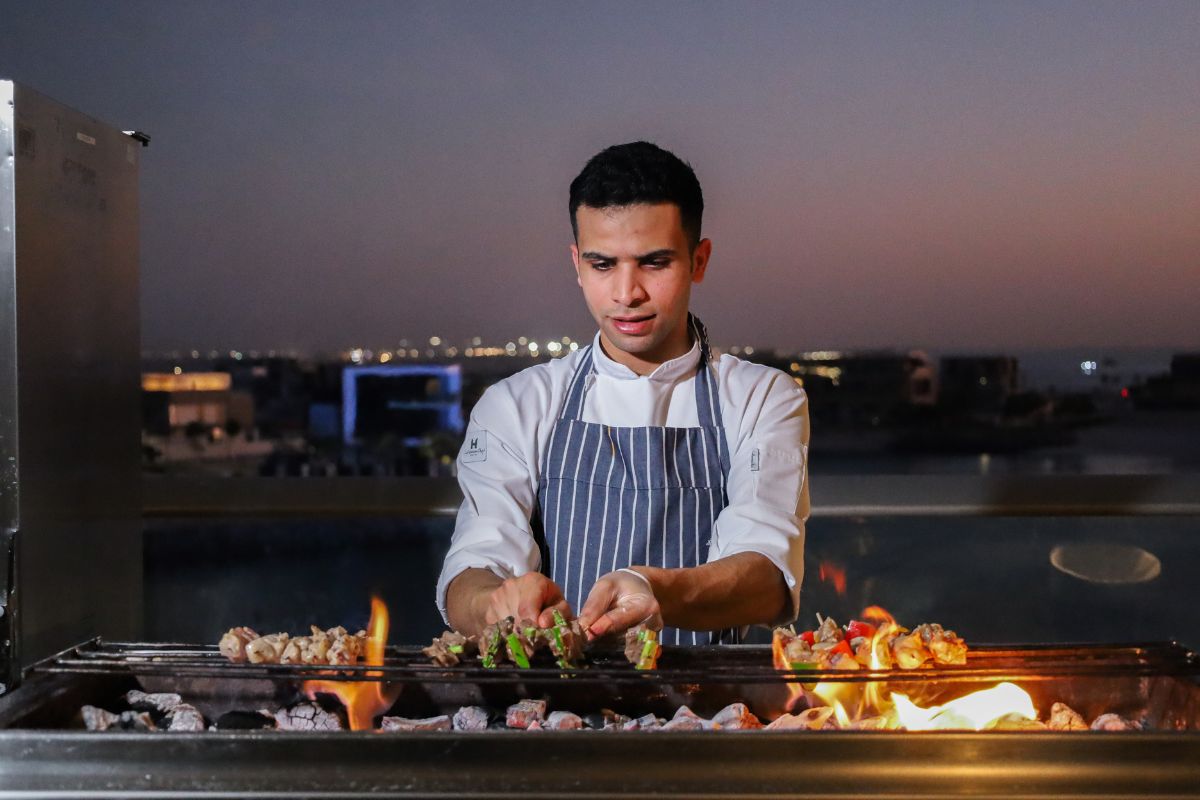 A chef grilling kebabs on an open flame for theme nights at Grand Hyatt Abu Dhabi summer offers