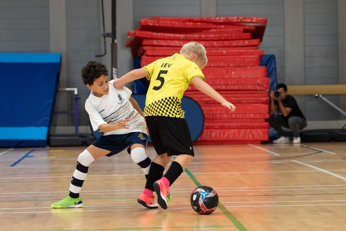 2 kids from the opposing team battling it out playing football at Abu Dhabi futsal leagues finals this weekend