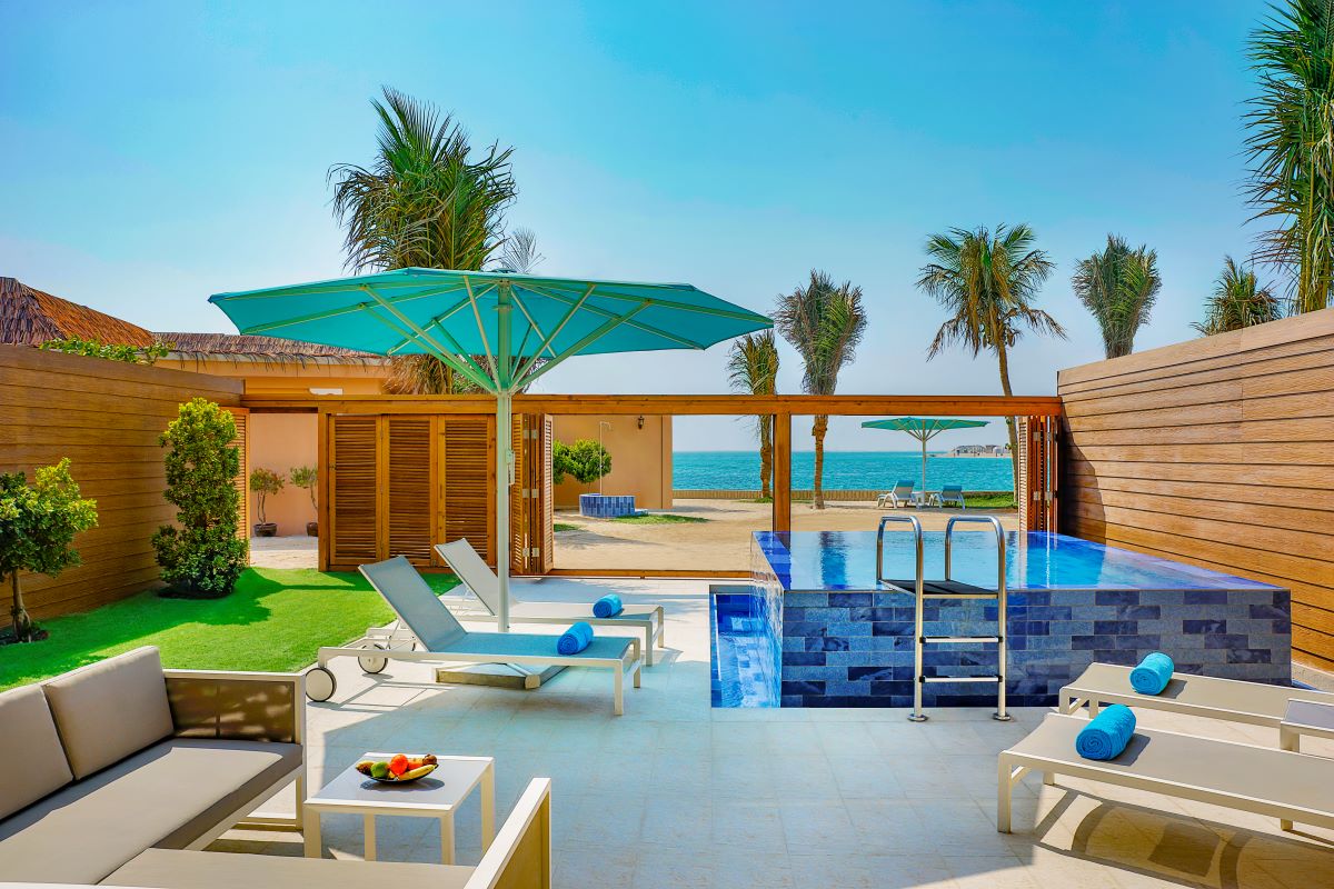 A view with trees, vibrant umbrella, small pool and chairs and tables at Anantara World Islands Dubai Resort for staycation in the UAE