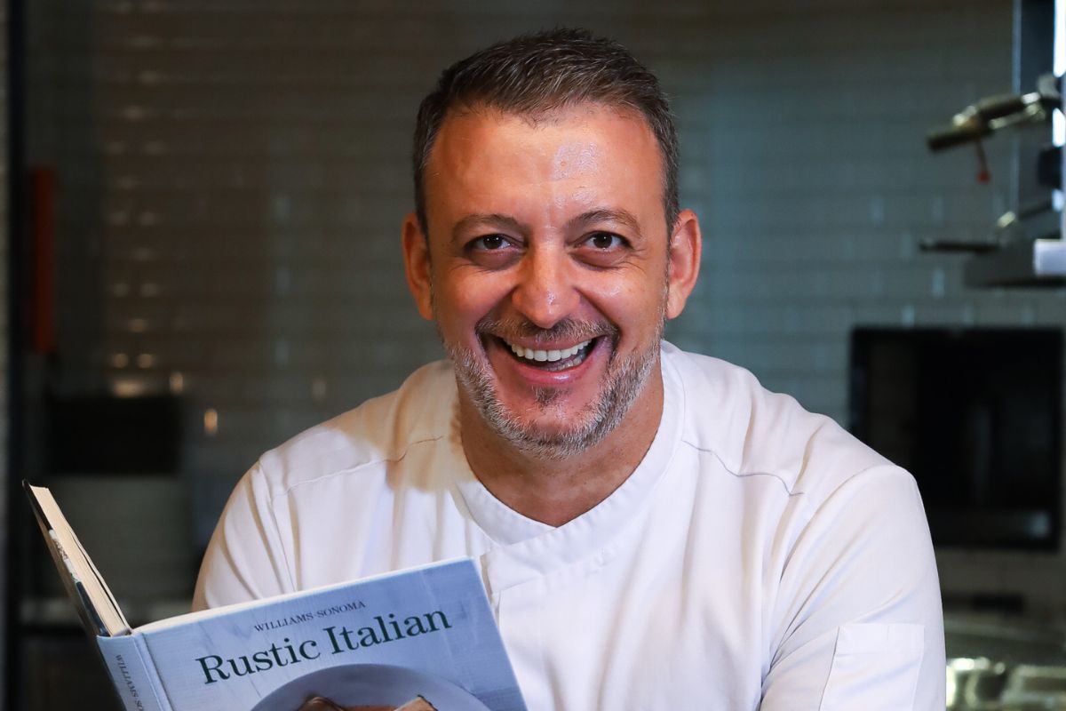 Chef Andrea Fioravanti of Grand Hyatt Abu Dhabi Hotel and Residences Emirates Pearl grinning while holding a rustic Italian cookbook