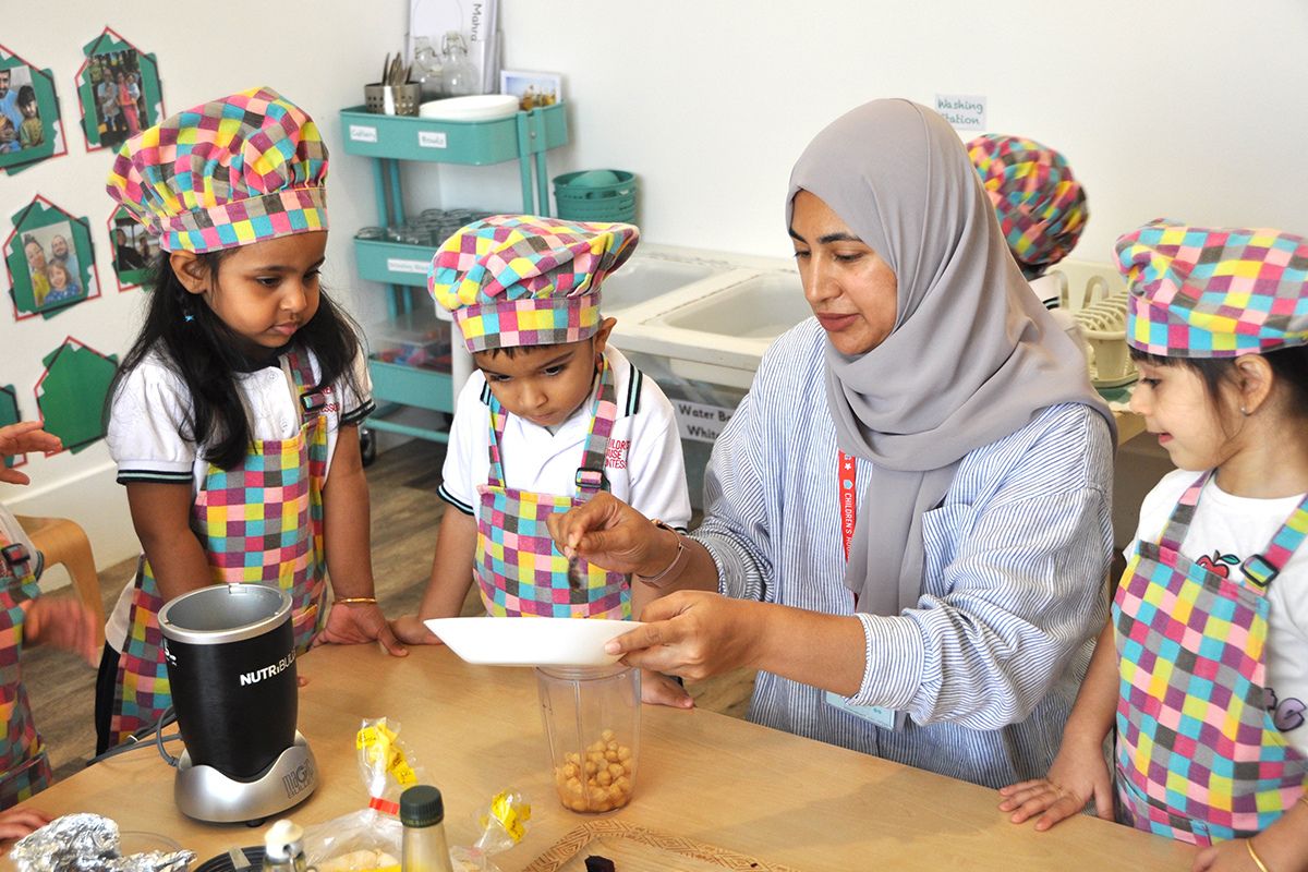 A teacher in class with the students of Children's House Montessori summer camps making hummus with equipments