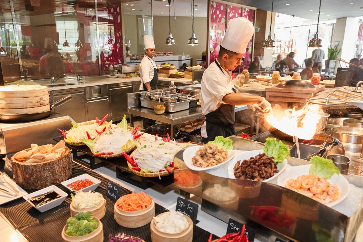 A chef at Fairmont Bab Al Bahr cooking and tossing up a flavourful dish surrounded by fresh ingredients for Eid Al Adha dining offers