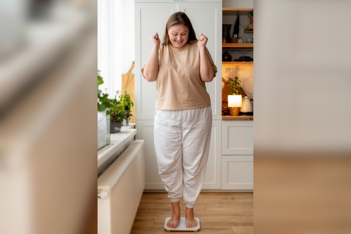 A lady on a scale happily reacting to her weight for weight management at UE Medical Health Plus