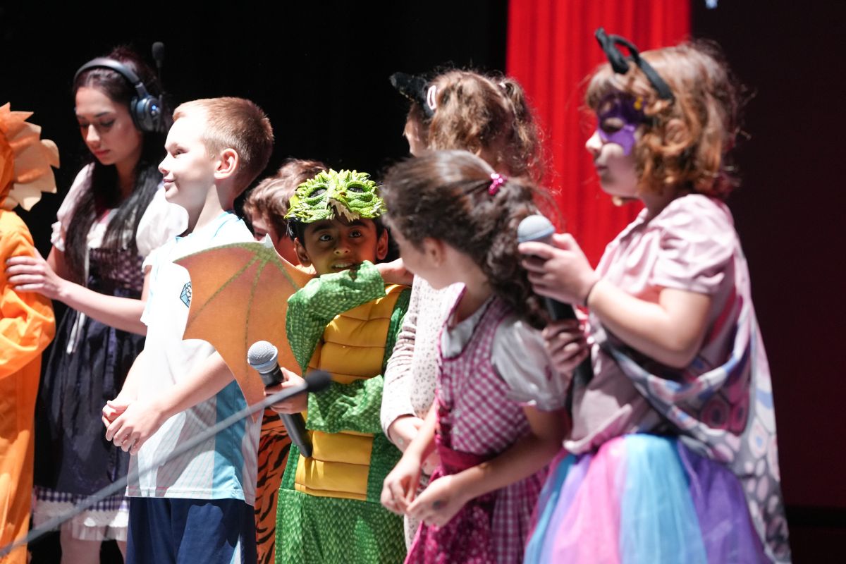 Children on stage wearing colourful costumes and performing at Nord Anglia International School Abu Dhabi for World Languages Day