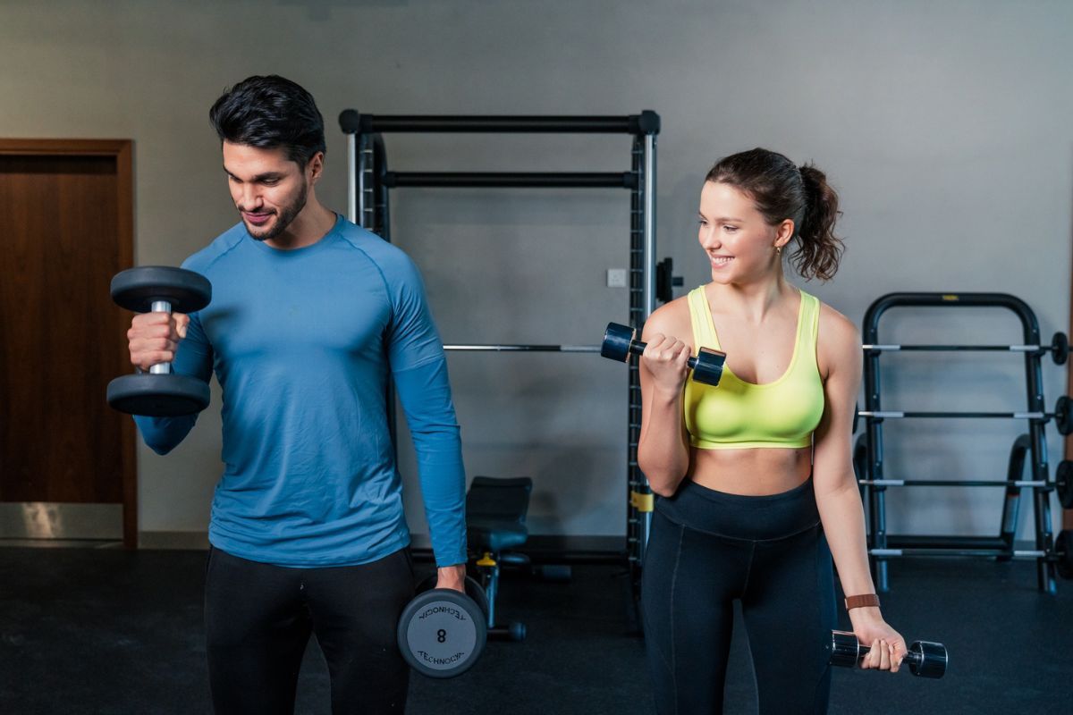 Couple lifting weights in a gym, one of Yas Acres Golf and Country Club membership benefits