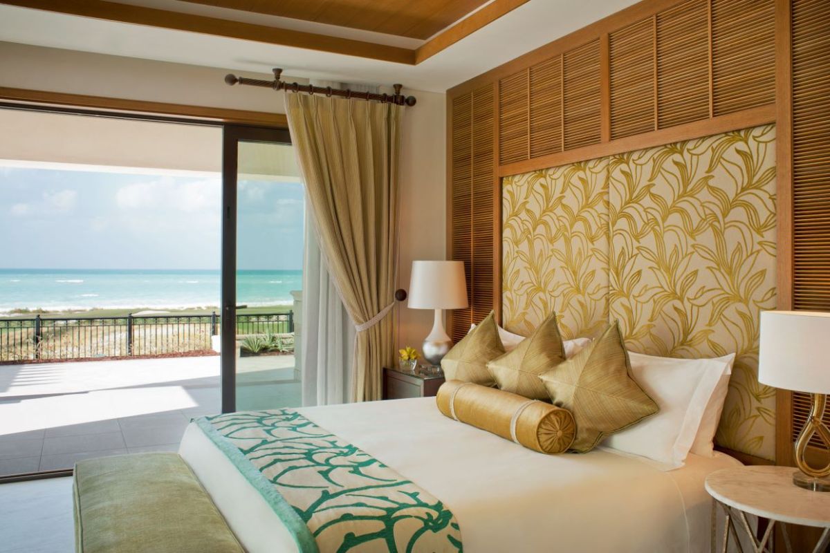 Majestic Suite interior design with golden headboard, pillows and decours, amazing view at the balcony at St. Regis Saadiyat Island Resort