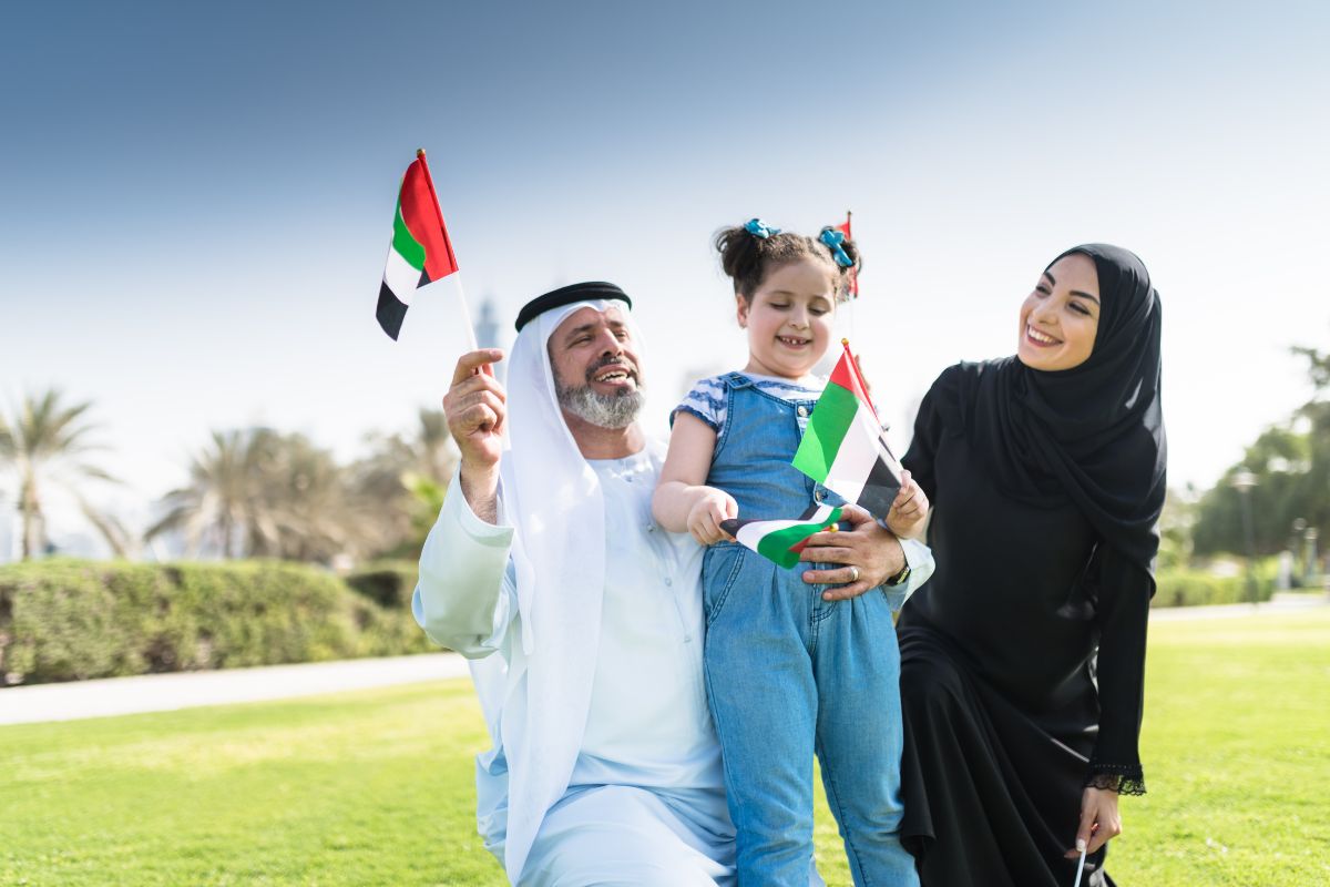 Emirati family waving a flag for UAE public holidays this 2025