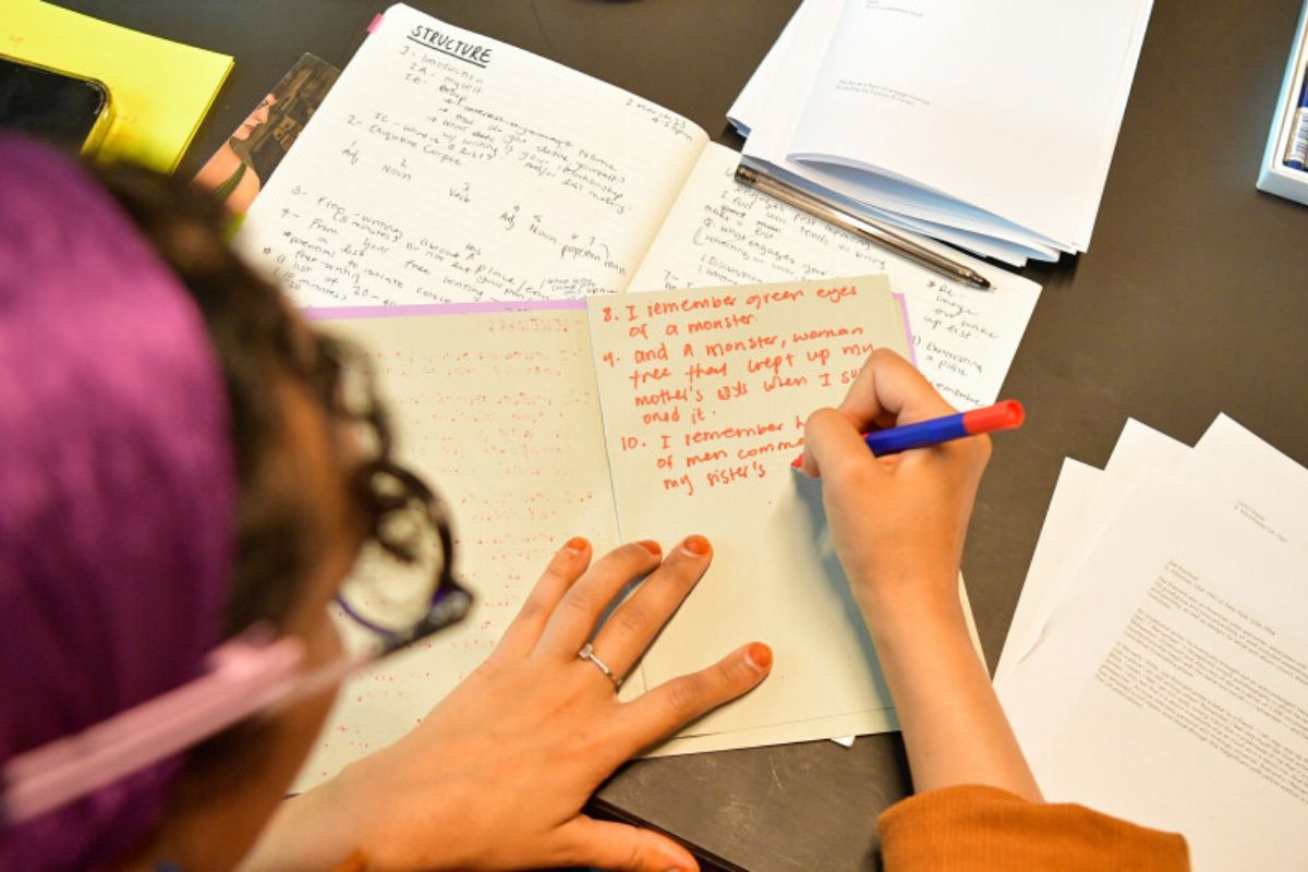 A lady writing on a notebook for Writing Circle - Pencil In A Writers’ Group 421 Summer programmes 2024