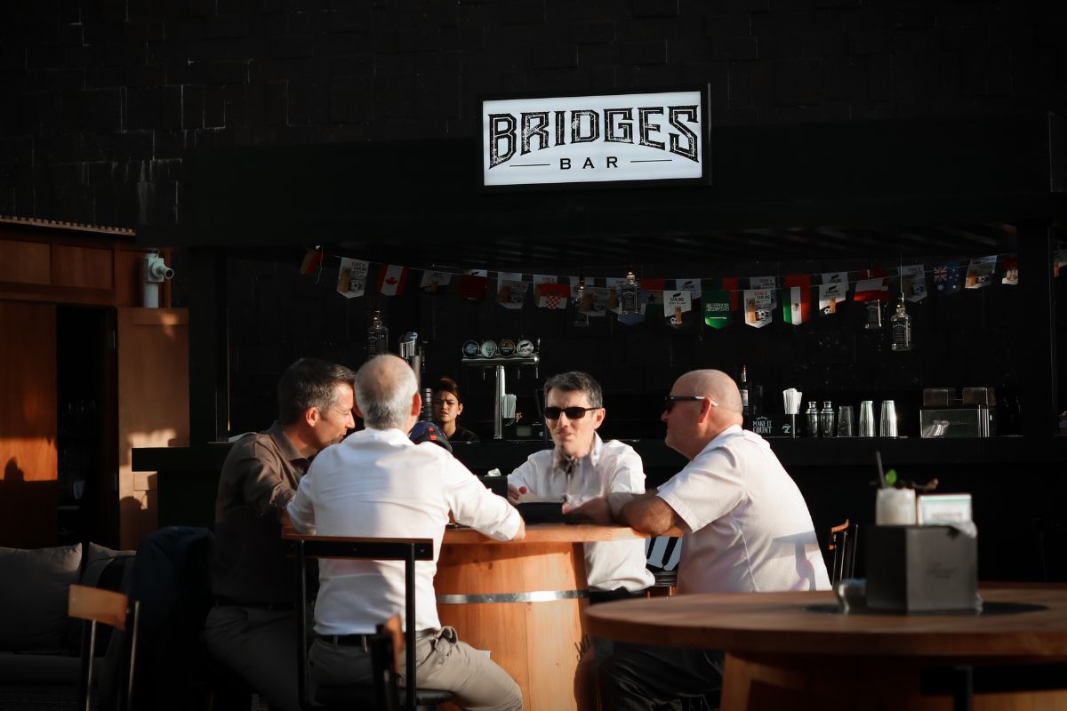 Four men sitting at a barrel table drinking for the best happy hour in Abu Dhabi at Bridges Bar Fairmont Bab Al Bahr Abu Dhabi