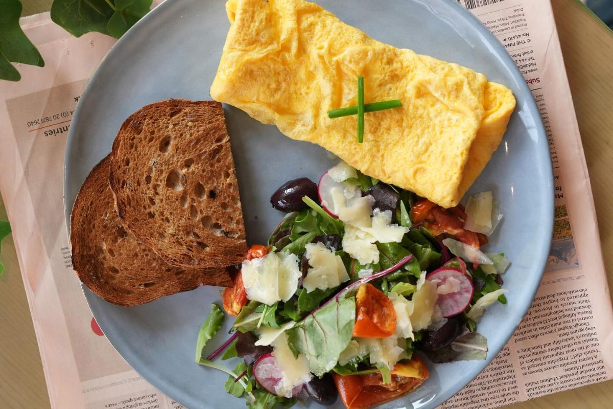 A breakfast plate with a brown bread, fluffy omelette and a side salad for Circle Cafe one of the best breakfast offers in Abu Dhabi