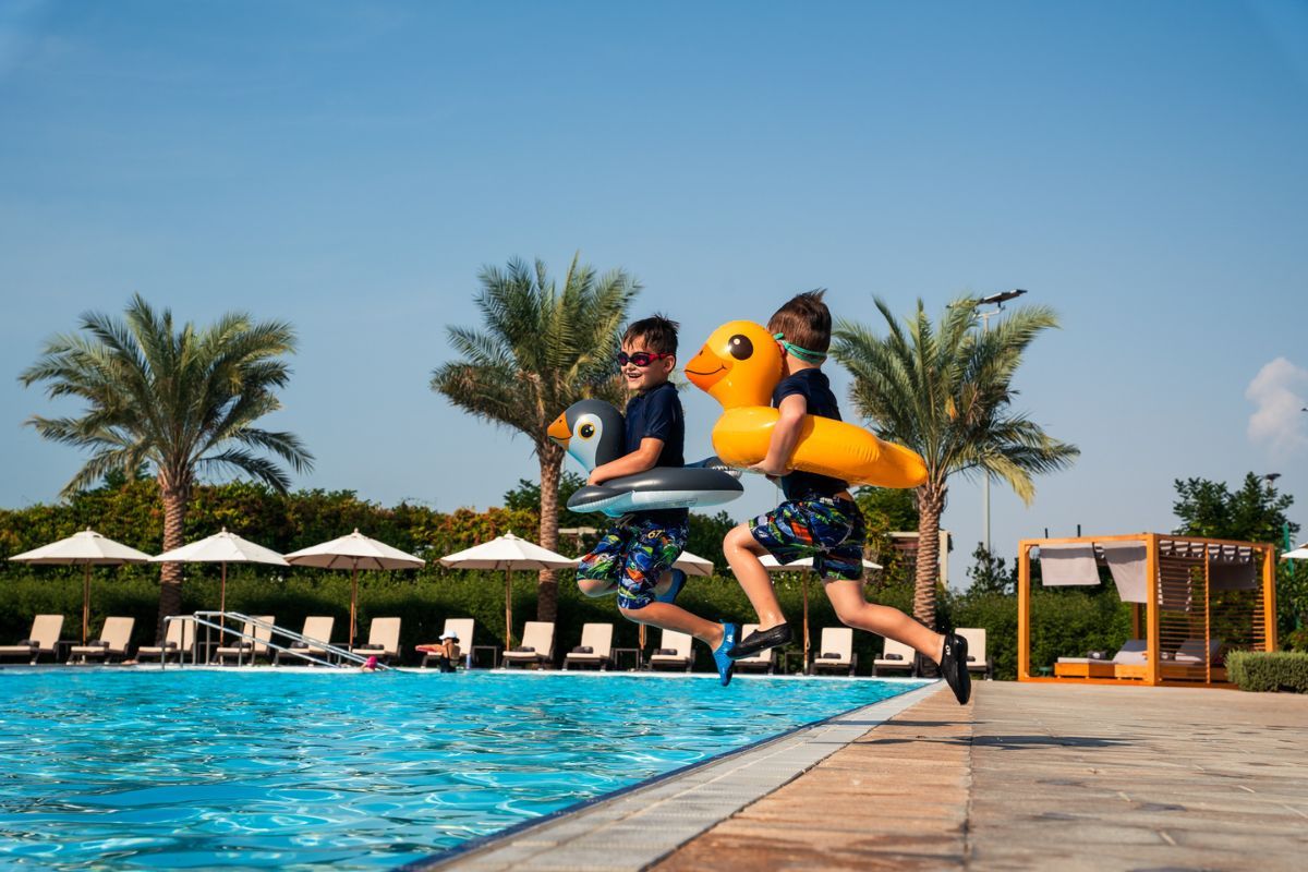 Summer Pool Party at Yas Acres Golf and Country Club featuring two kids jumping to the pool with their floaties