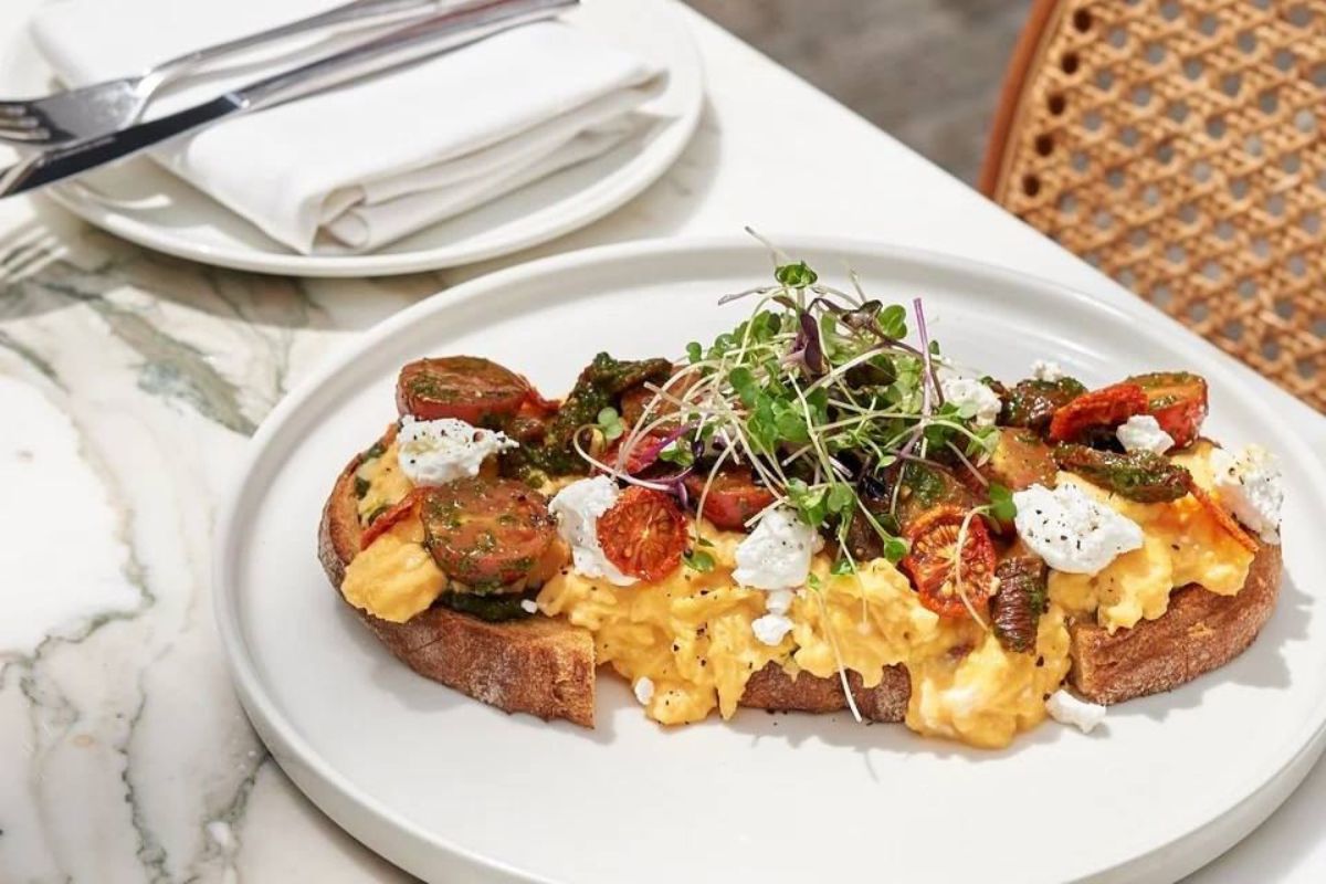 Tashas' St Francis breakfast. Scrambled eggs, goat cheese, cherry & sun-dried tomatoes in a basil pesto dressing, served on toasted village bread for the best breakfast offers in Abu Dhabi