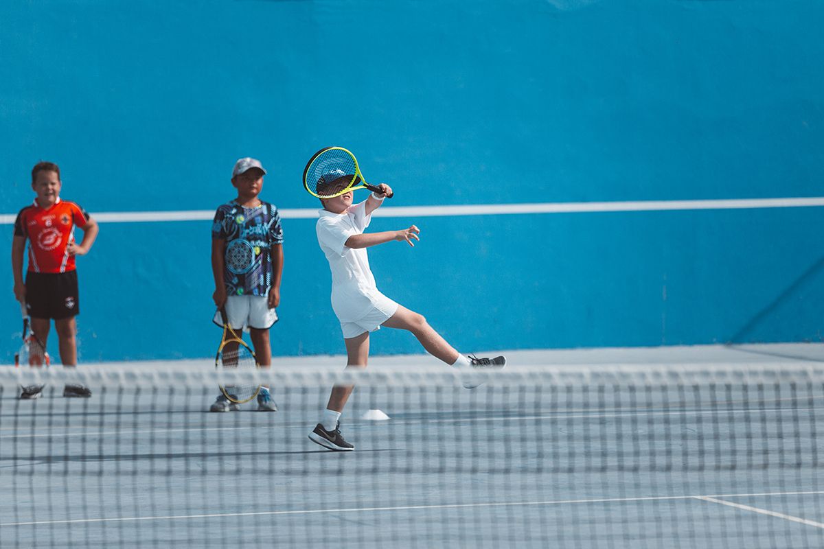 Kids playing tennis at a court at The Club Abu Dhabi summer camp