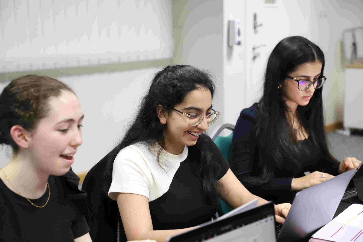 IB Students at computer smiling at BIS Abu Dhabi