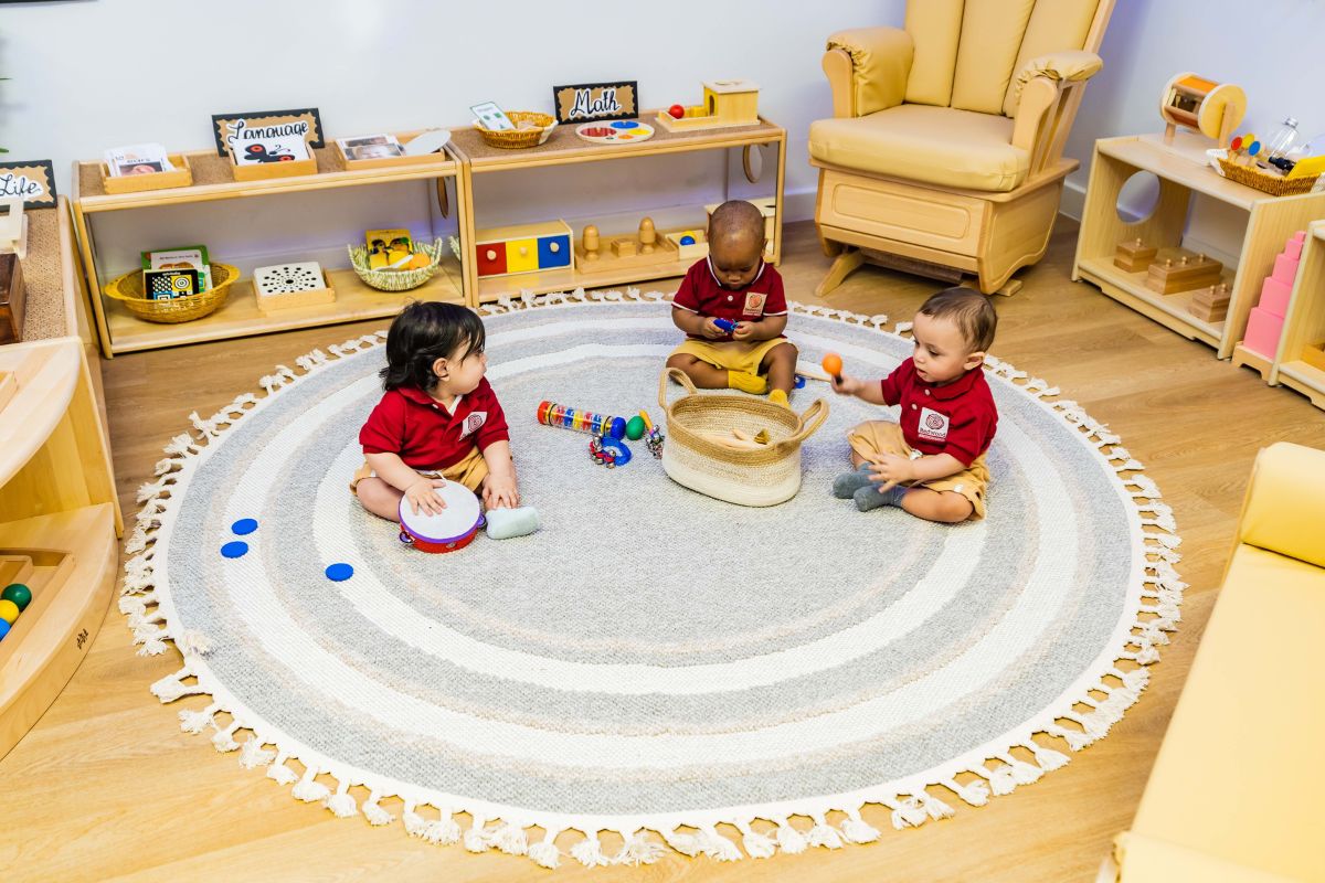 Children sitting on the floor playing with one another at The Redwood Montessori Nursery