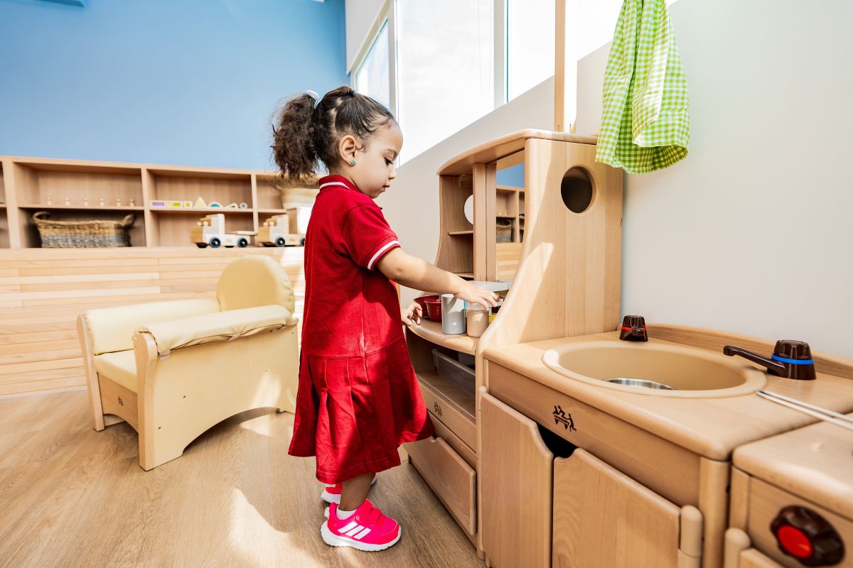 A kid playing on a pretend kitchen at The Redwood Montessori Nursery