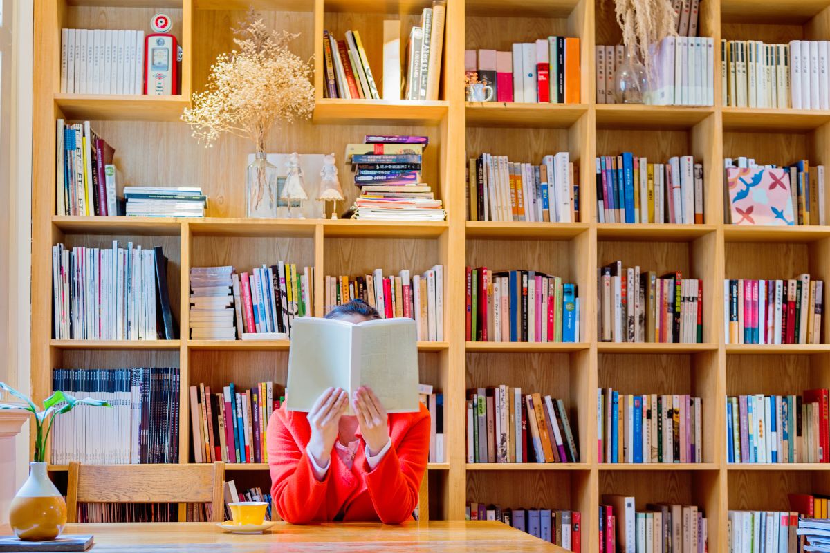 A lady in the library holding and reading a book for International Literacy Day