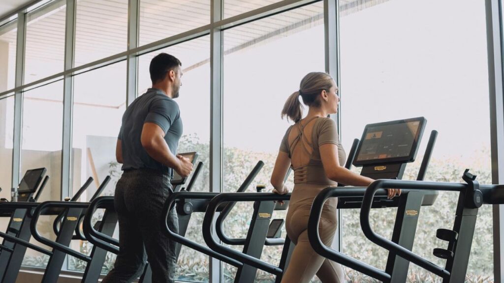 one of the best gyms in abu dhabi this 2025 featuring etizan fitness, couple of gym people running on threadmill