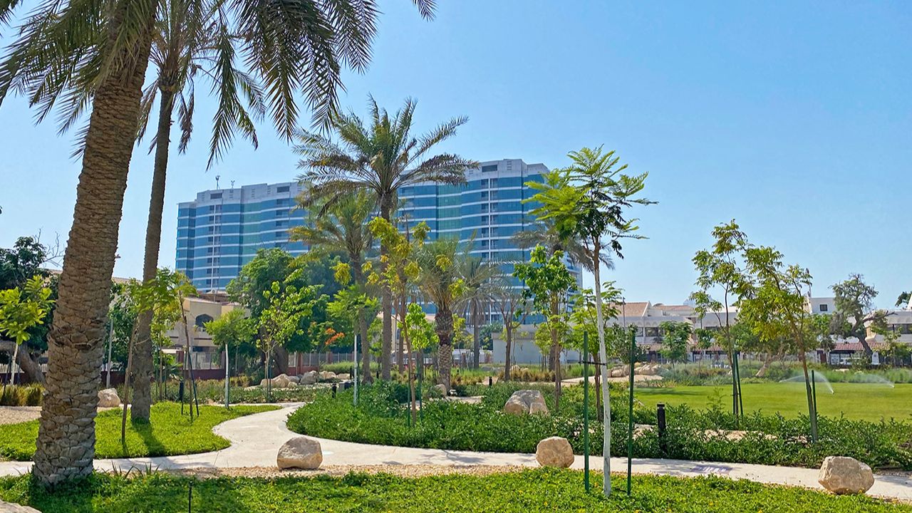 Sheikha fatima park abu dhabi with trees and a building in the background