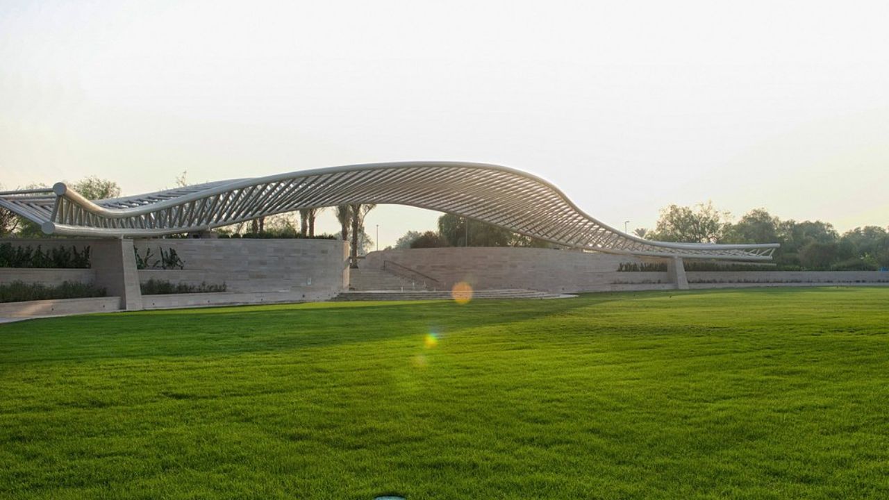 A green grass field with a curved structure umm al emarat park abu dhabi