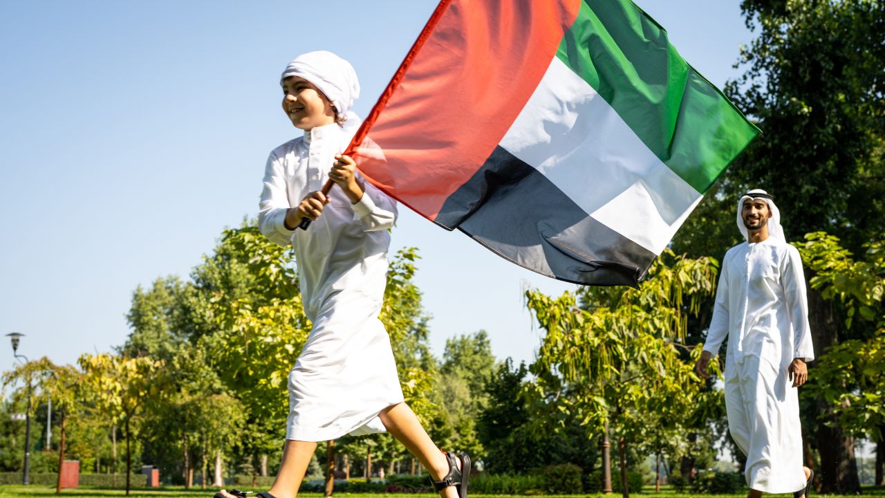 kid running in the park with UAE flag