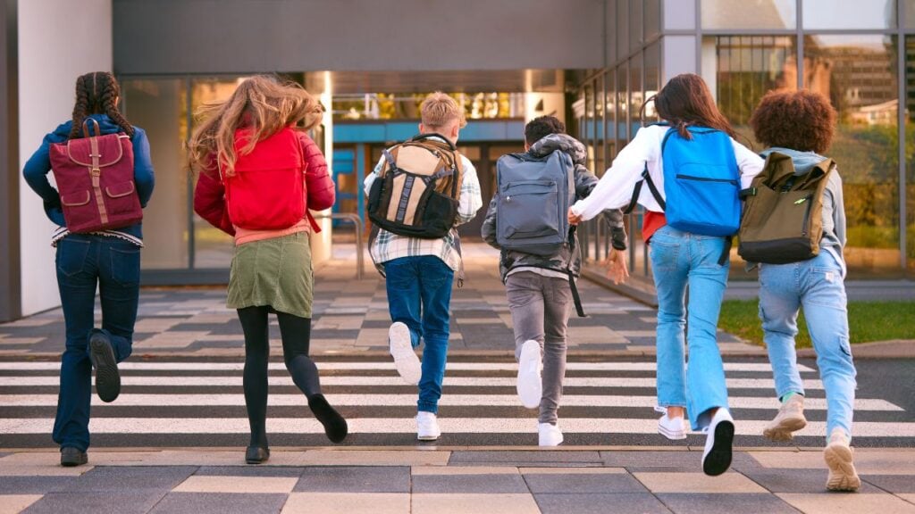 Group Of Secondary Or High School Pupils Running Away From Camera Outside School Building