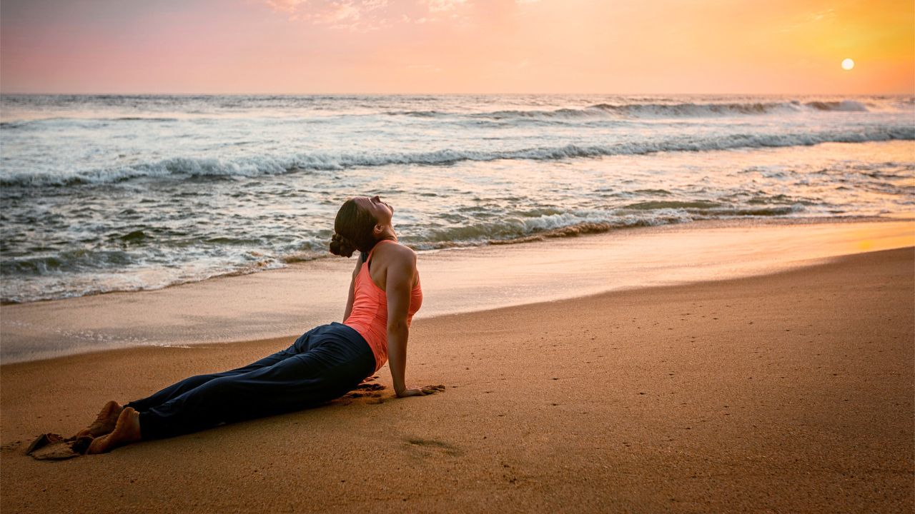woman practicing yoga on the beach