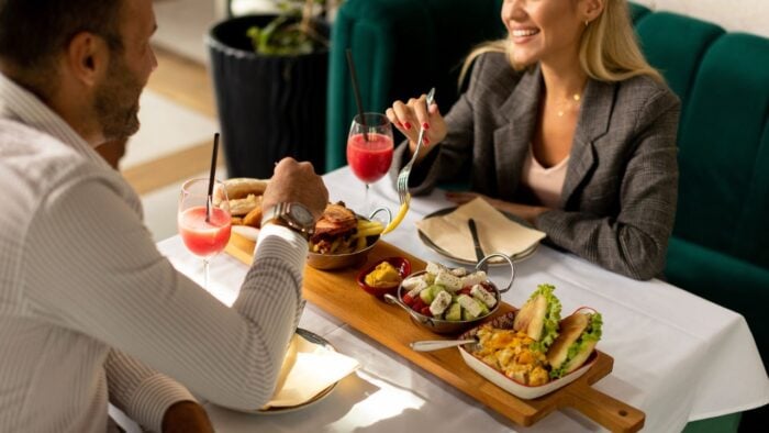 Two people enjoying business lunch with drinks and food in Abu Dhabi restaurant.