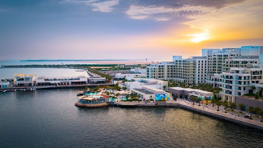 Yalla Abu Dhabi Life: Yas Bay waterfront with modern buildings and sunset view.