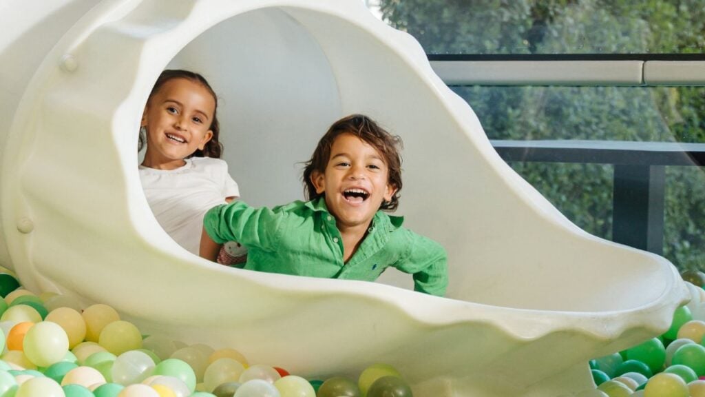 two children going down a slide at Little Acres Kids Club, Yas Acres Golf & Country Club