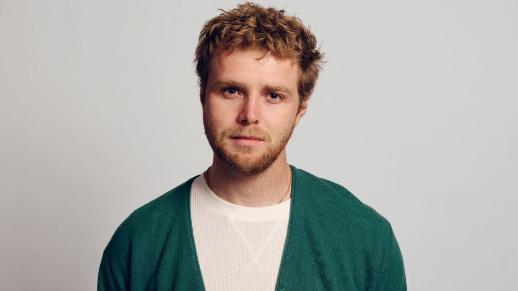 Young man with curly hair, serious expression.