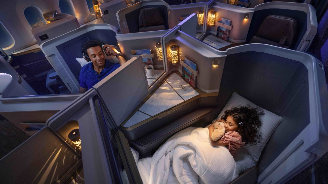 Passengers on the business class, a kid sleeping and a man watching a movie with his headphones