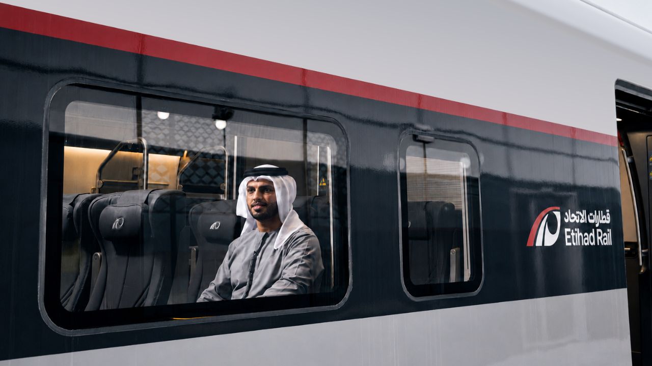 Emirati guy sitting inside Etihad Rail train looking out the window