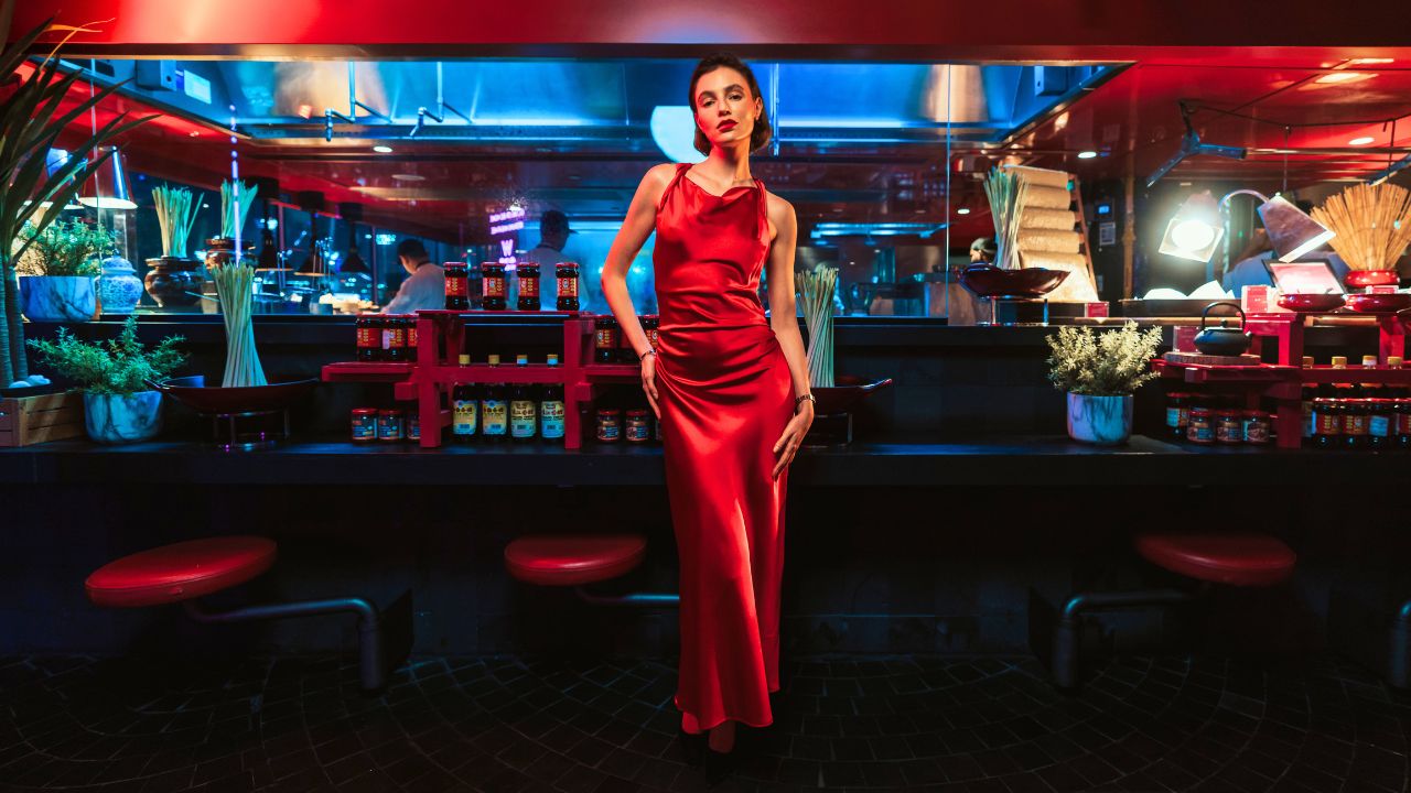 A lady in red dress standing in the middle of a restaurant