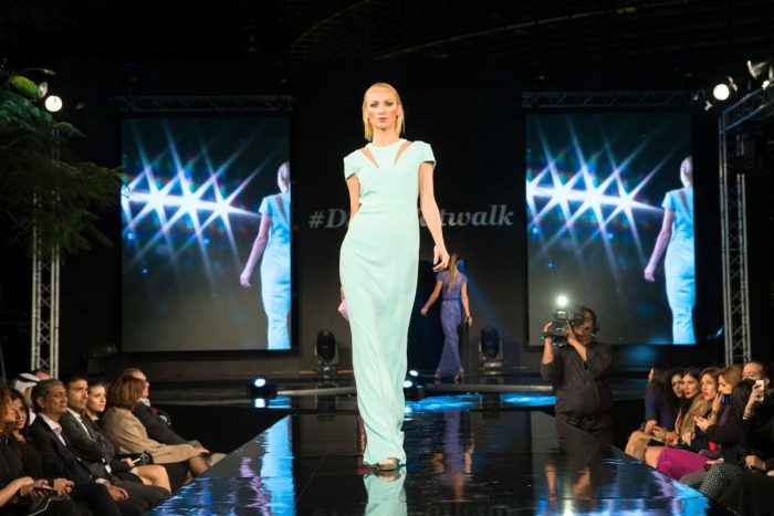 a lady on the runway with spectators on the side for a fashion show