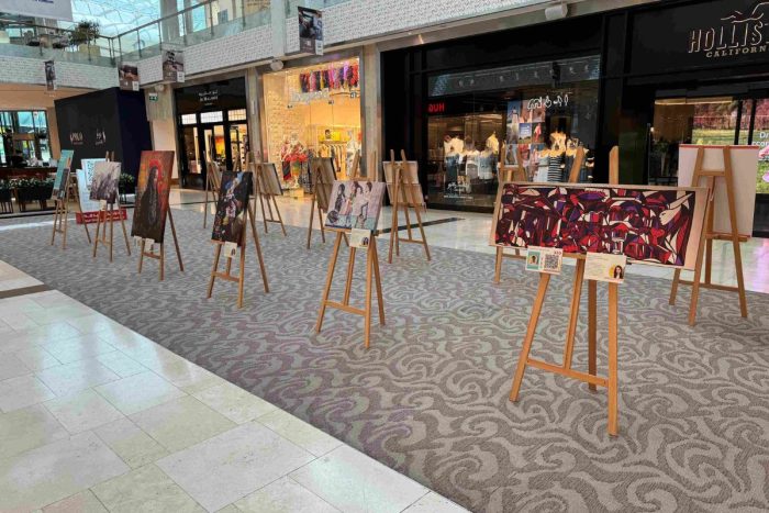 Paintings and artworks on easel stands displayed by BIS Abu Dhabi at Yas Mall for an art exhibition