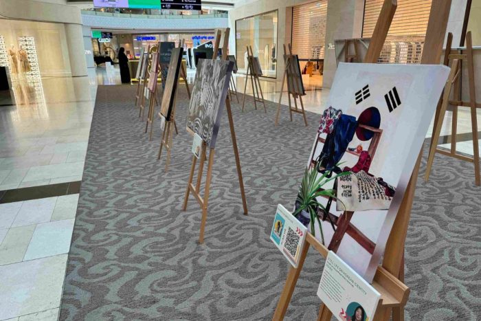 Paintings and artworks on easel stands displayed by BIS Abu Dhabi at Yas Mall for an art exhibition