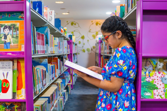 An Arabic girl reading a book in a library at MAKTABA Summer Camp 2022